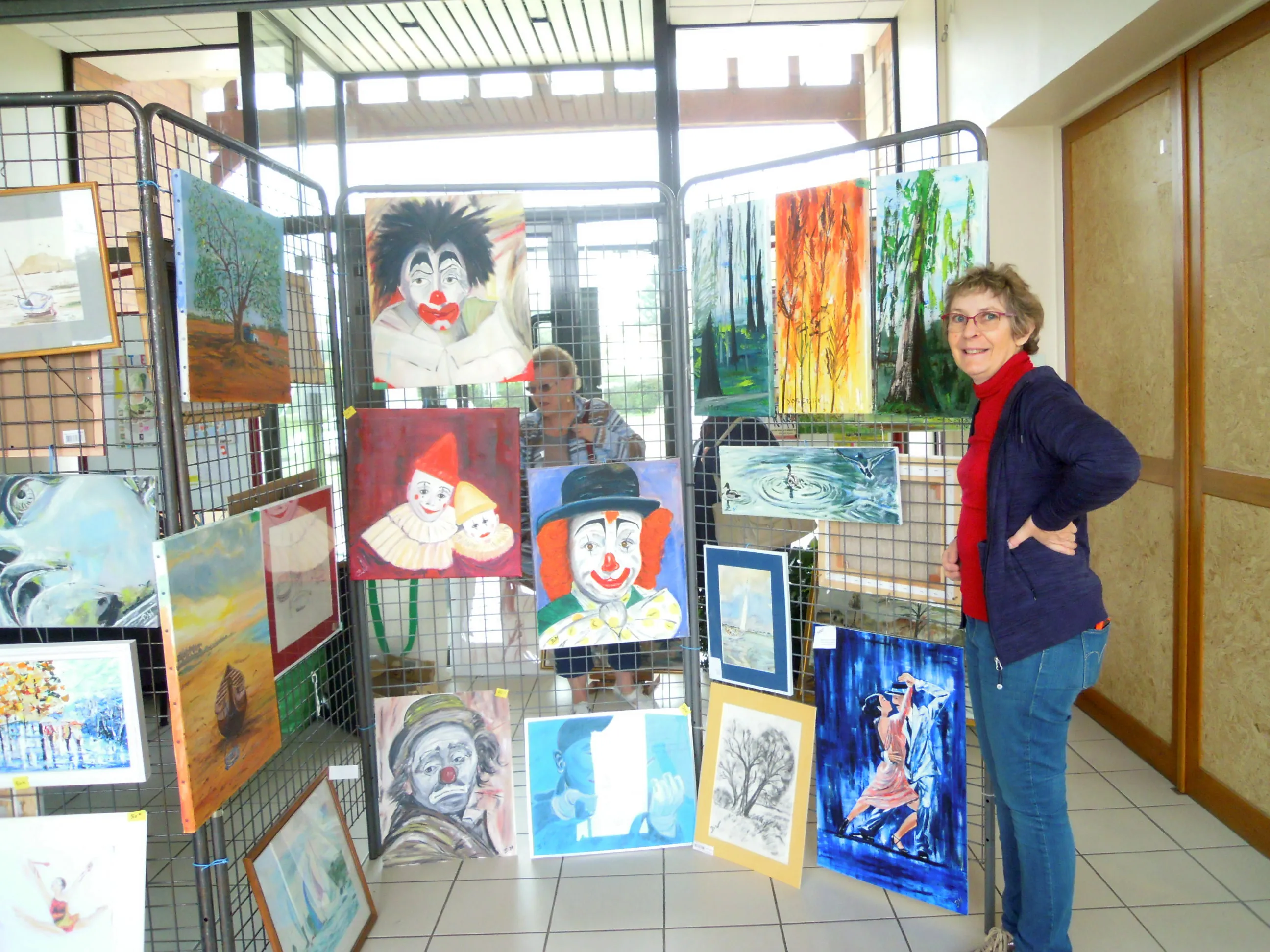 Béatrice, debout devant ses toiles lors d'une exposition au profit de l'AMRO.